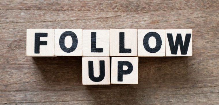 Wooden blocks arranged to spell the words "FOLLOW UP" against a wooden background. The blocks have black letters on them, creating a clear and straightforward message about the importance of following up.