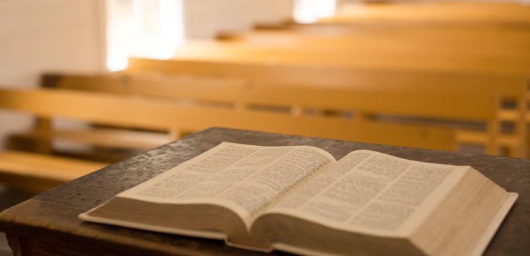 Bible on wooden pulpit with pews in background