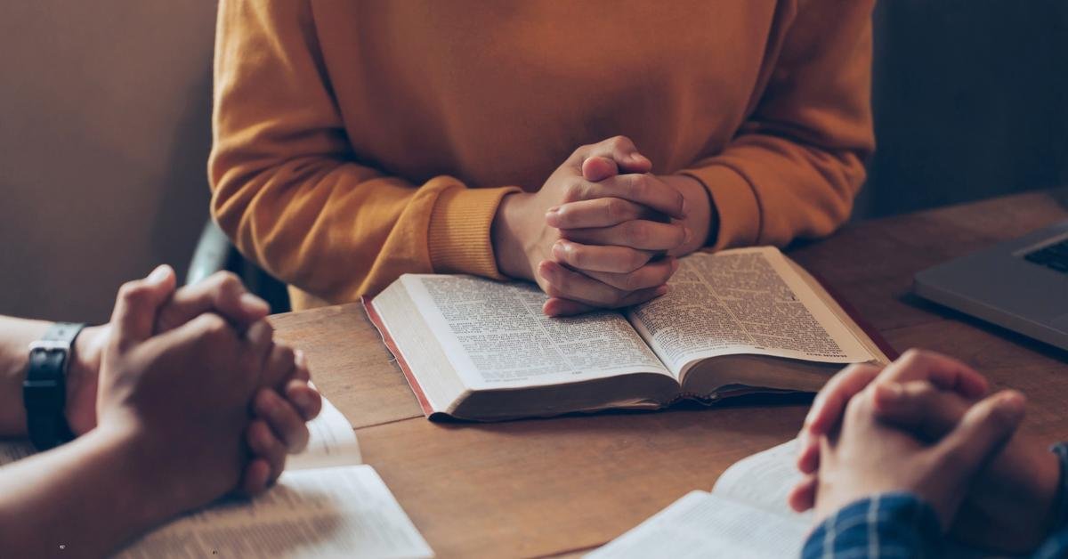 Family praying at table, folded hands