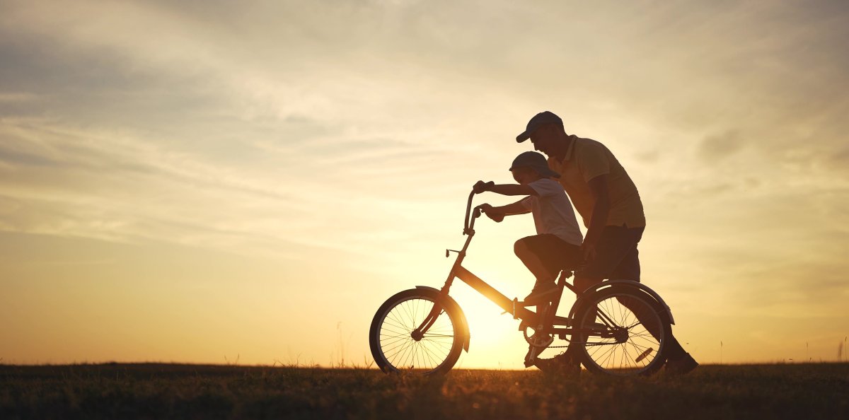 Dad teaching son to ride a bike.
